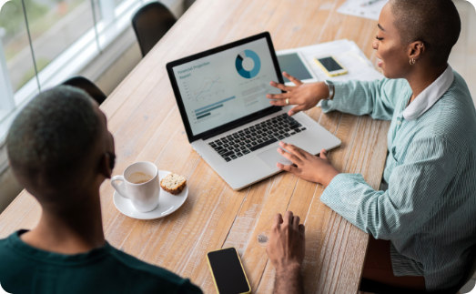 Two coworkers discussing data shown on a laptop screen.