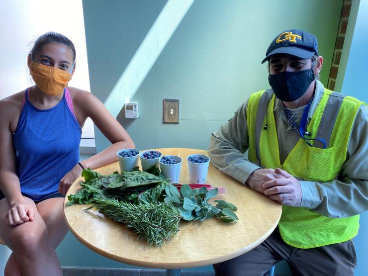 <p>Miriam Campbell and Steve Place with their respective group's donations to the Klemis Kitchen. Credit: Students Organizing for Sustainability</p>