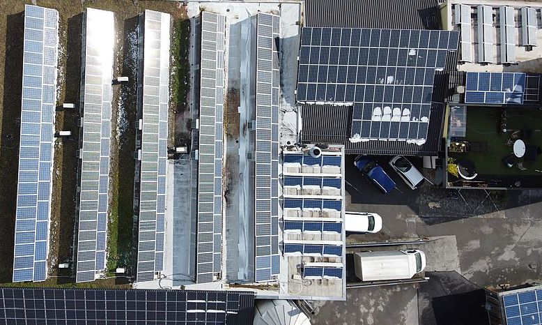 Aerial view of a commercial building with roof-mounted solar panels. Image credit: Asurnipal, CC BY-SA 4.0 &lt;https://lnkd.in/ddzprHi&gt;, via Wikimedia Commons