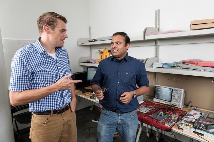 <p>Justin Romberg, a professor in Georgia Tech’s School of Electrical and Computer Engineering, and Arijit Raychowdhury, an associate professor in the School of Electrical and Computer Engineering, with the newly-developed low-power camera. (Credit: Rob Felt, Georgia Tech)</p>