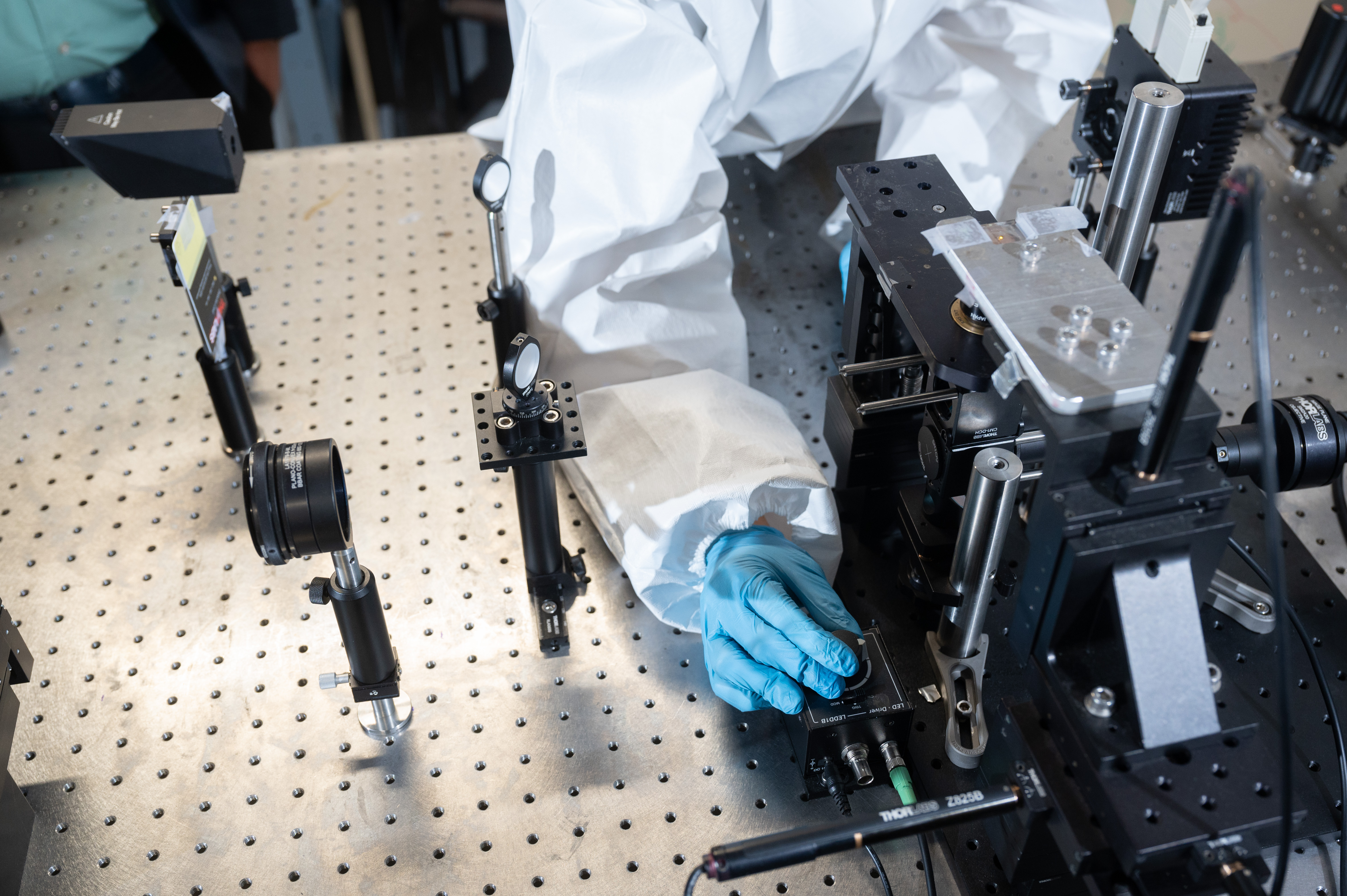 A gloved hand adjusts a dial on a piece of equipment