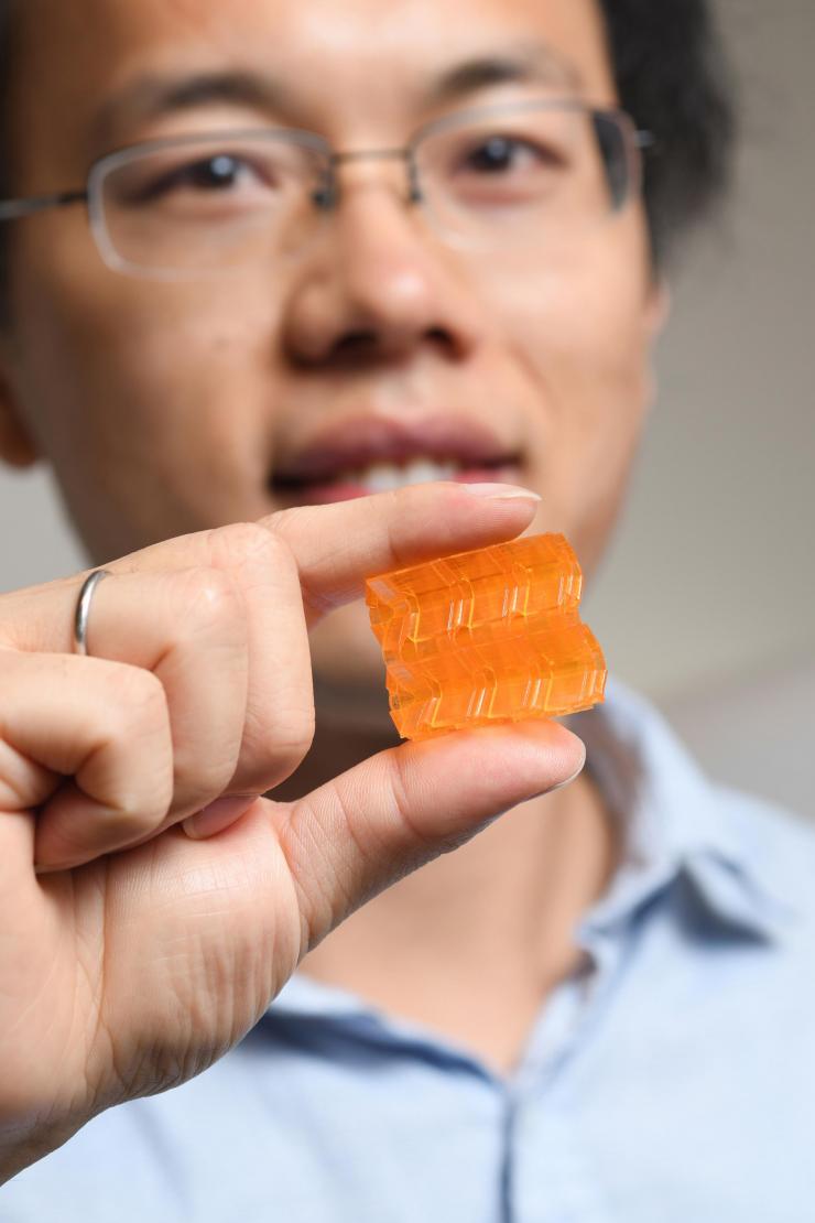 <p>Georgia Tech postdoctoral fellow Xiao Kuang demonstrates the compressibility of origami structures created through Digital Light Processing 3D printing. (Credit: Christopher Moore, Georgia Tech).</p>