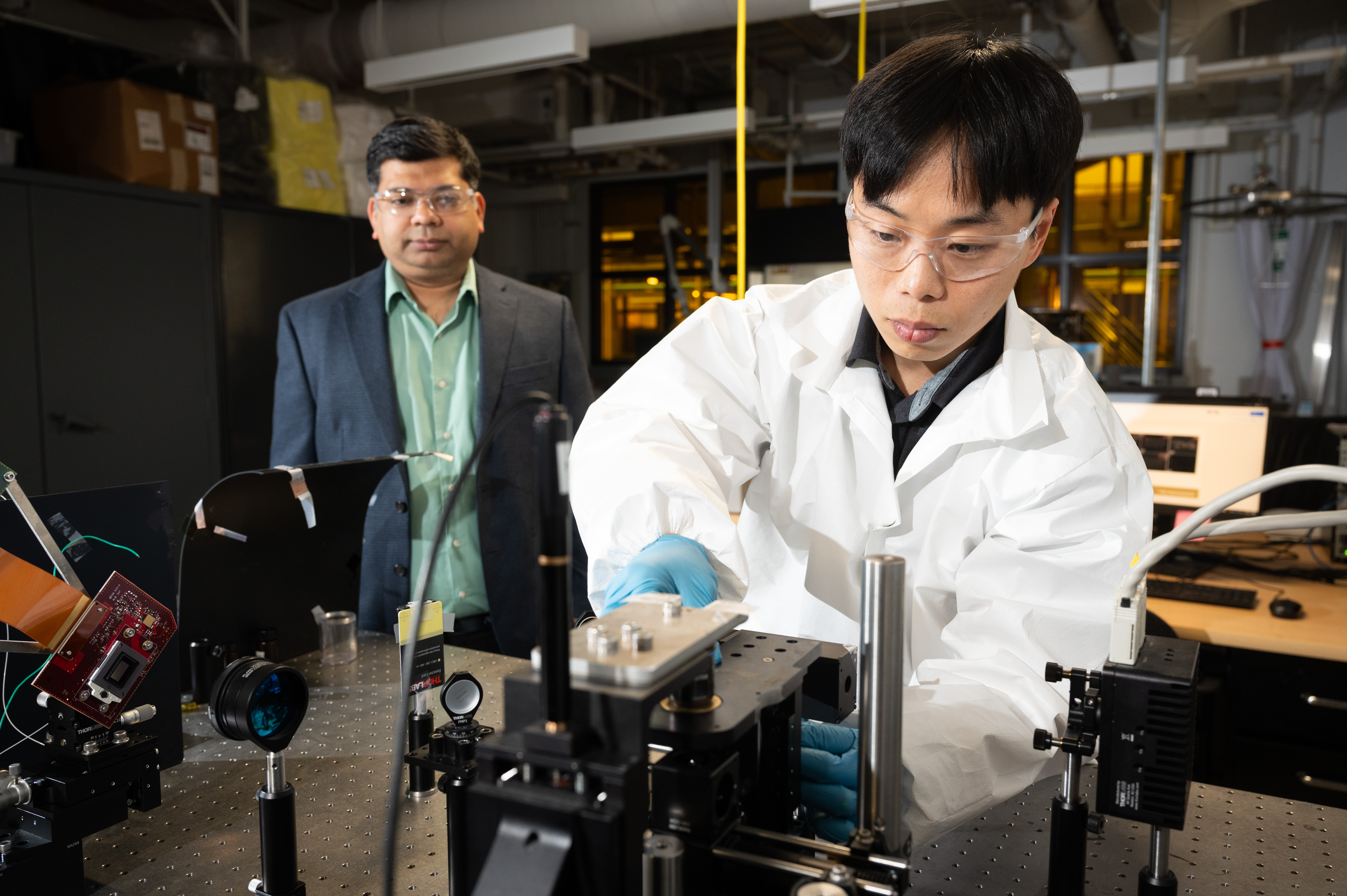 Two men in a lab and one of them is adjusting a piece of equipment