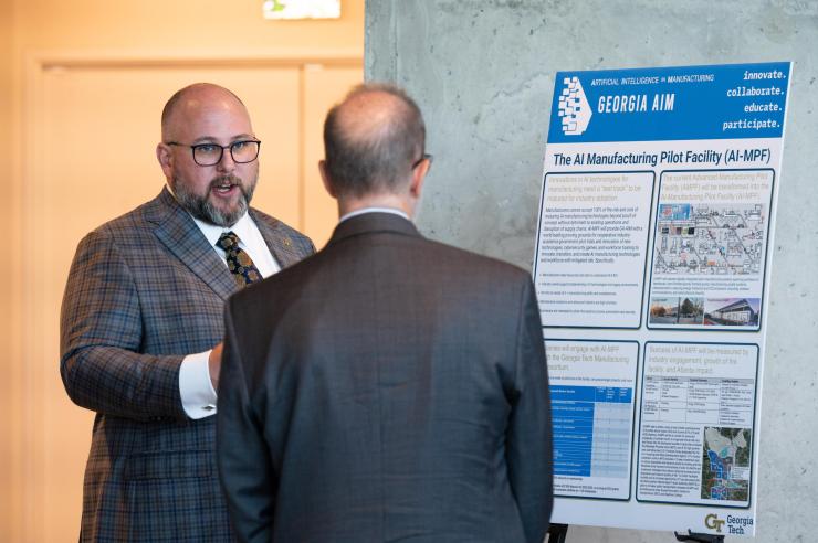 <p>Aaron Stebner (left), associate professor in the <a href="https://www.me.gatech.edu/">George W. Woodruff School of Mechanical Engineering</a> and Georgia AIM co-lead, discusses how the AI Manufacturing Pilot Facility (AI-MPF) advances Georgia AIM goals with Dennis Alvord, the Economic Development Administration’s deputy assistant secretary for economic development and chief operating officer. (PHOTO: Joya Chapman)</p>