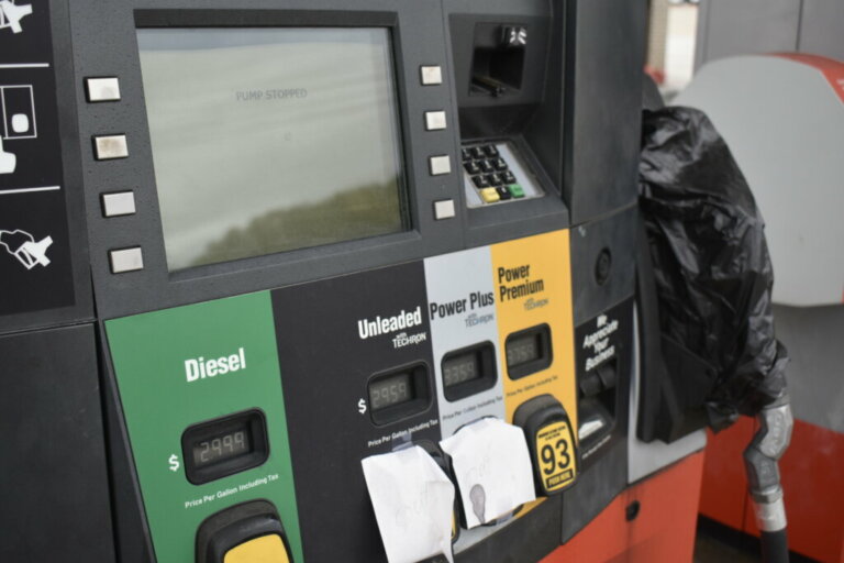 Picture of an empty gasoline pump with a bagged spout and paper signs taped to it.