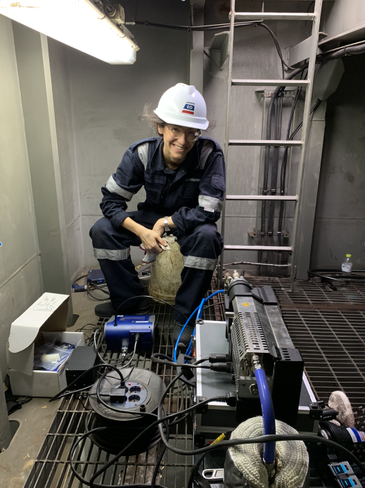 A woman sits in the funnel of a ship, taking particulate measurements. 