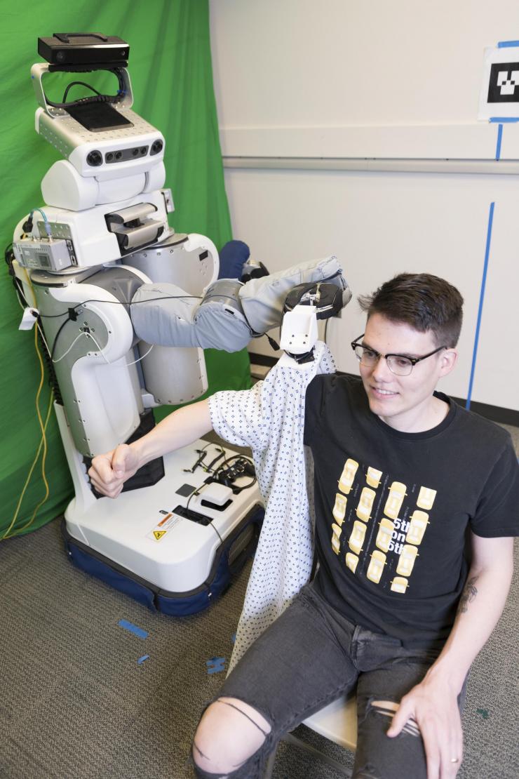 <p>Left to right: Zackory Erickson, a PR2 robot, and Charlie Kemp</p>