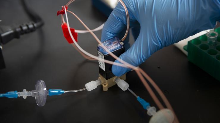 <p>A microfluidic system concentrates a fluid sample that would contain particles collected from the air of an office building. In a fully operating system, the fluid would be analyzed for the presence of SARS-CoV-2, the virus that causes COVID-19. (Credit: Christopher Moore, GTRI)</p>