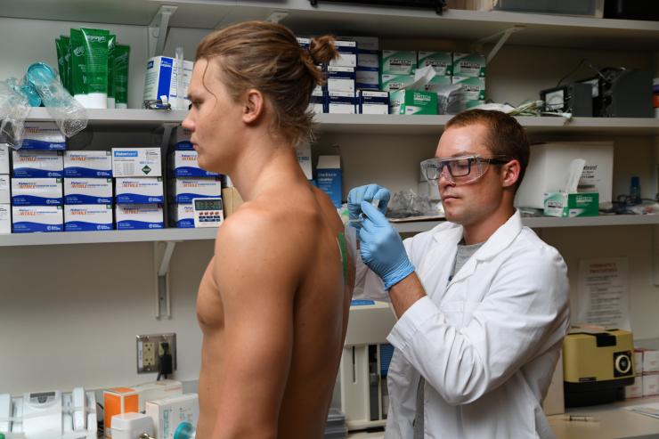 <p>A research scientist withdraws sweat from a pouch on the back of a volunteer. Sweat is analyzed for electrolyte concentration among other biochemicals in Mindy Millard-Stafford's exercise physiology lab in Georgia Tech's School of Biological Sciences. Credit: Georgia Tech / Christopher Moore</p>