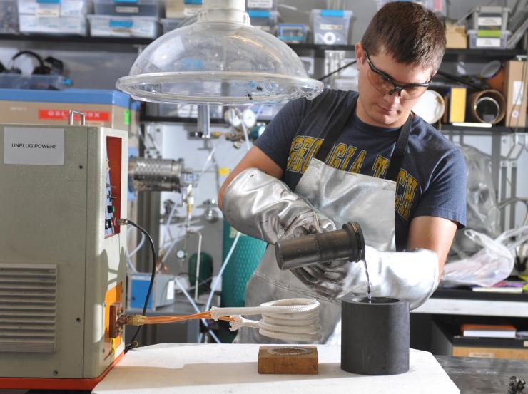 <p>Graduate Student Caleb Amy pours molten tin into a crucible in the laboratory of Asegun Henry at Georgia Tech. A new ceramic-based pump designed and tested at Georgia Tech was used to transfer molten tin at more than 1,400 degrees Celsius. (Credit: Christopher Moore, Georgia Tech)</p>