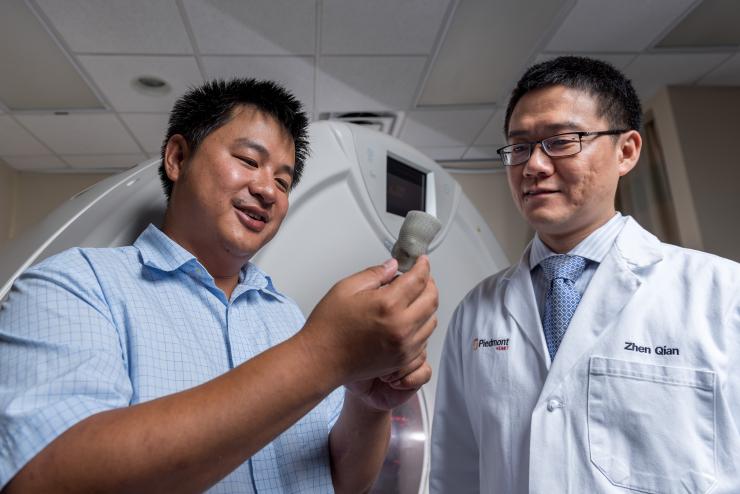 <p>Kan Wang, a postdoctoral researcher at Georgia Tech, and Zhen Qian, chief of cardiovascular imaging research at Piedmont Heart Institute, inspect a printed heart valve. (Credit: Rob Felt, Georgia Tech)</p>