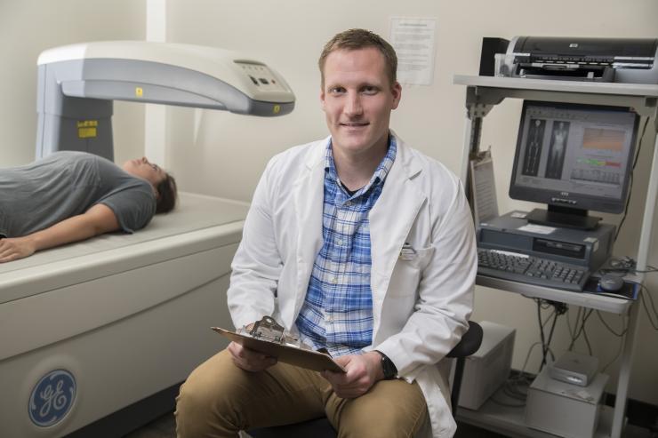 <p>Matt Wittbrodt sits at a device that measures body composition. He is keenly interested in workplace accident risk factors possibly produced by dehydration and exertion and the ensuing decline in physical and cognitive abilities. Wittbrodt received his doctoral degree at Georgia Tech and is a postdoctoral research assistant at Emory University. Credit: Georgia Tech / Christopher Moore</p>