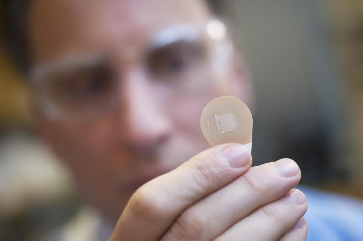 <p>Mark Prausnitz, Ph.D., Georgia Tech Regents professor in the School of Chemical and Biomolecular Engineering, holds a microneedle vaccine patch containing needles that dissolve into the skin. (Credit: Christopher Moore, Georgia Tech)</p>