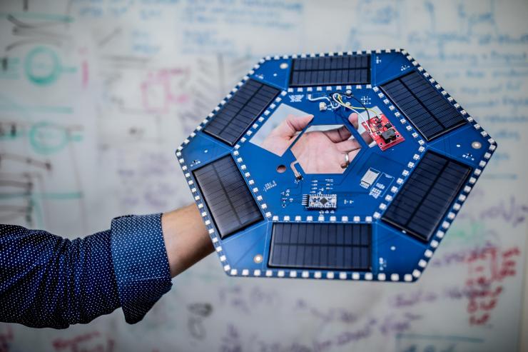 <p>Ilan Stern, a GTRI senior research scientist, holds examples of the electronic components that will be used in piezoelectric tiles that will be used to create a lighted outdoor footpath at the NASA Kennedy Space Center’s Visitor Complex at Cape Canaveral, Florida. The tiles are powered by piezoelectric components that generate current when they are compressed, flexed or vibrated. (Credit: Branden Camp, Georgia Tech)</p>