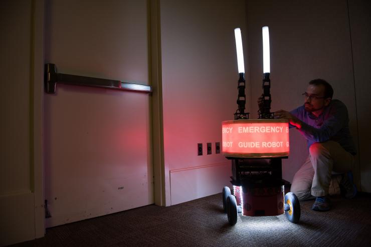 <p>Georgia Tech Research Institute (GTRI) Research Engineer Paul Robinette adjusts the arms of the “Rescue Robot,” which was built to study trust between humans and robots in emergencies. (Credit: Rob Felt, Georgia Tech)</p>