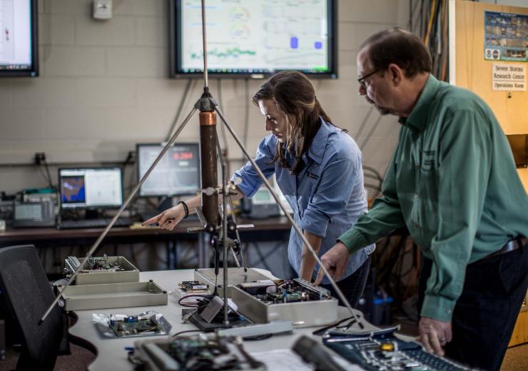 <p>John Trostel, director of the Severe Storms Research Center (SSRC), and Madeline Frank, a research meteorologist at the SSRC, examine equipment for the North Georgia Lightning Mapping Array, a network of 12 sensors located around the metropolitan Atlanta area to detect lightning that may indicate storm intensification. (Credit: Branden Camp, Georgia Tech Research Institute)</p>