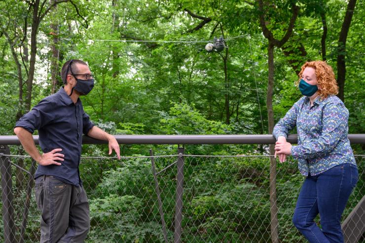 <p>Georgia Tech Professor and School Chair Magnus Egerstedt and Atlanta Botanical Garden Vice President for Conservation and Research Emily Coffey on the Canopy Walk with the SlothBot behind them. SlothBot is a slow-moving and energy-efficient robot that can linger in the trees to monitor animals, plants, and the environment below. (Credit: Rob Felt, Georgia Tech)</p>