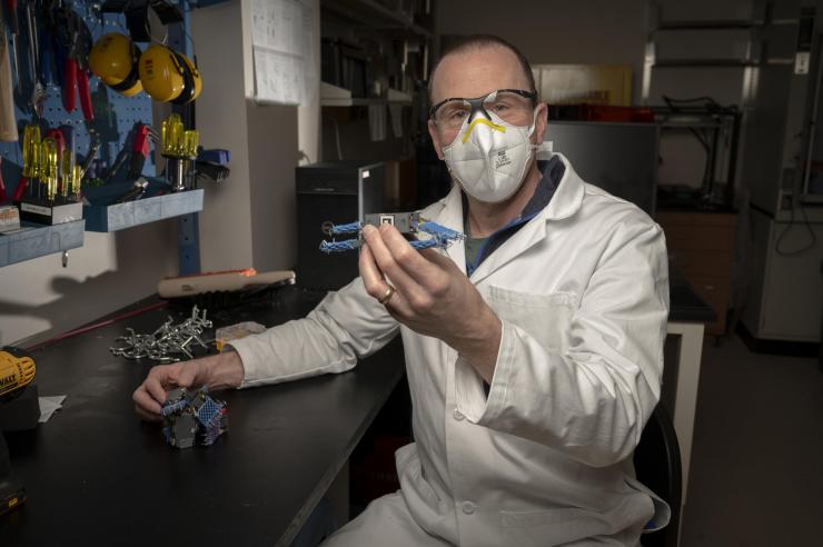 Georgia Tech Professor Daniel Goldman shows a smart active particle (smarticle), a simple robot used to study interactions similar to those of the “worm blobs” formed by California blackworms. (Credit: Christopher Moore, Georgia Tech)