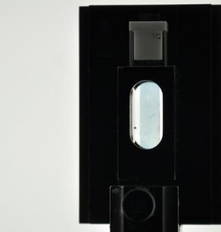 A strip of transparent conductive polymer held in a square black holder with an oval window in the middle. (Photo Courtesy: James Ponder)