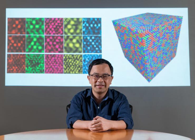 <p>Ting Zhu, professor of mechanical engineering at Georgia Tech, in front of his TEM images of polycrystalline metals and a graphic simulating atomic structure</p>