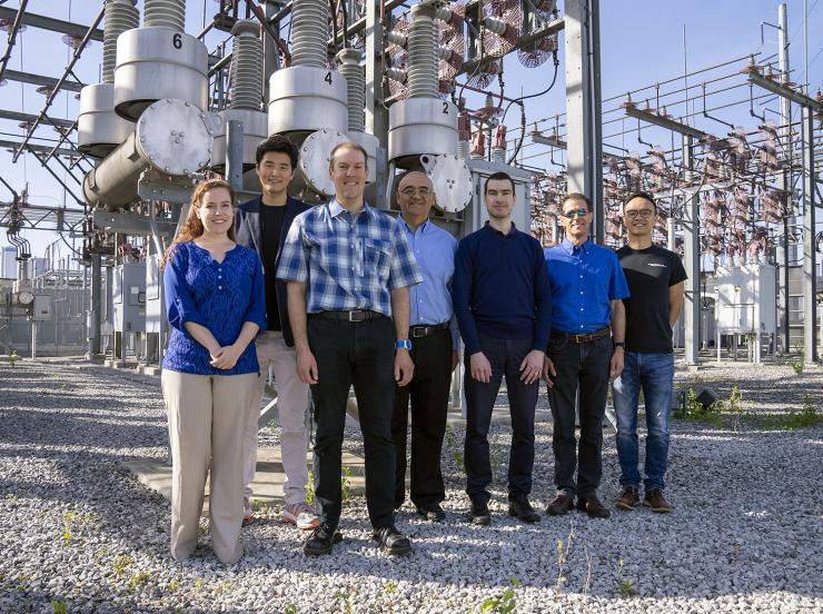 The TESLA (Tough and Ecological Supercritical Line Breaker for AC) team in front of high-voltage circuit breakers. 