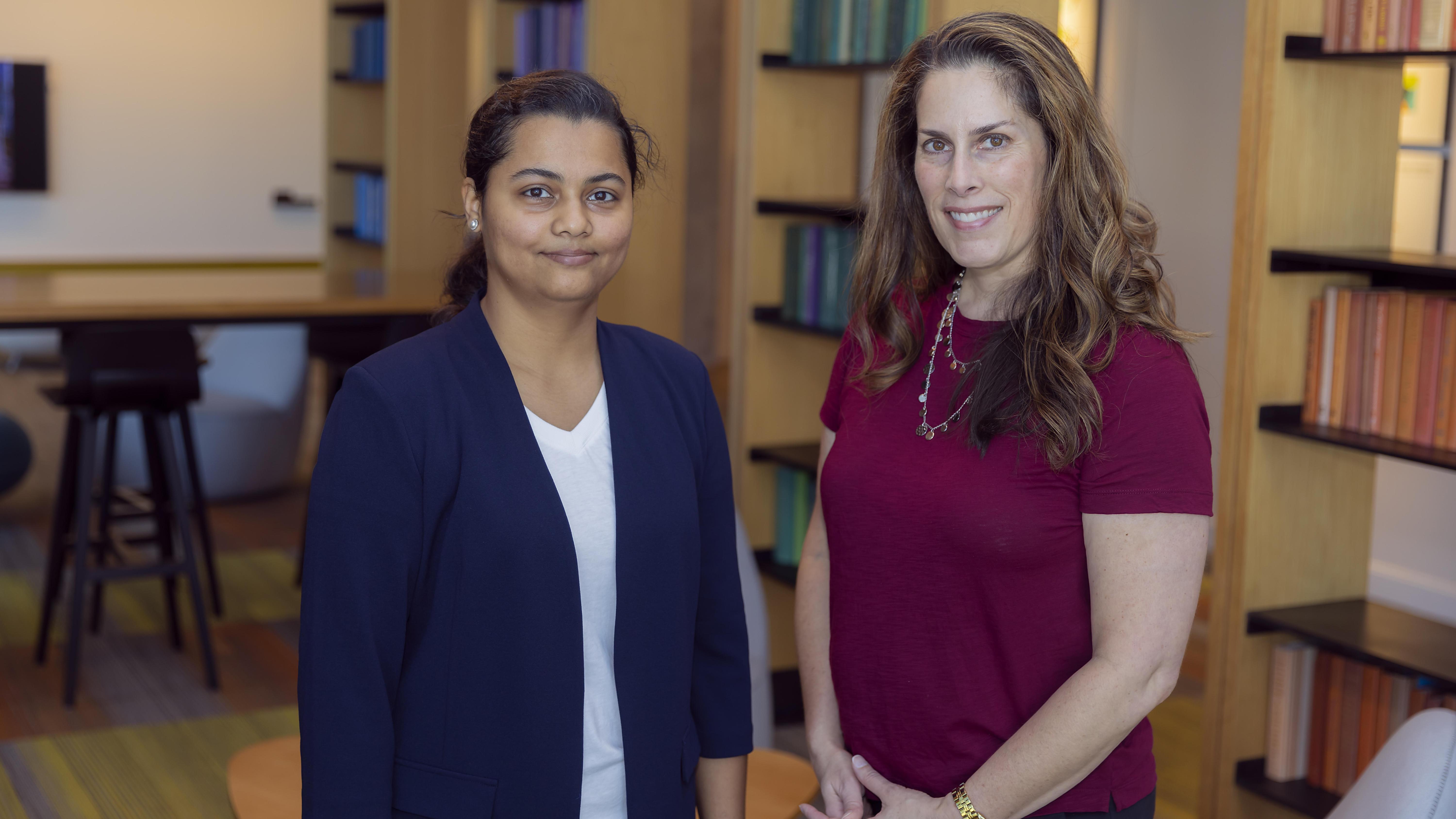 Two women standing in front of bookshelves 