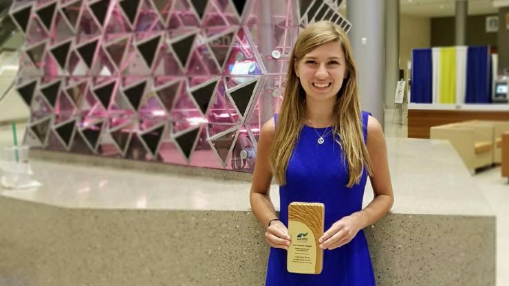 <p>Grace Brosofsky, BSEnvE 2017, stands with her Student Sustainability Leadership award from the Association for the Advancement of Sustainability in Higher Education. She won the award for a project she created with Engineers for a Sustainable World at Georgia Tech researching natural weed-control options. (Photo Courtesy: Grace Brosofsky)</p>