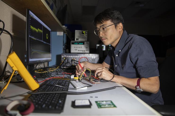 <p>GTRI researcher Paul Jo checks an RF test board with FCBGA packaged single-channel T/R module chips. (Credit: Sean McNeil, GTRI)</p>