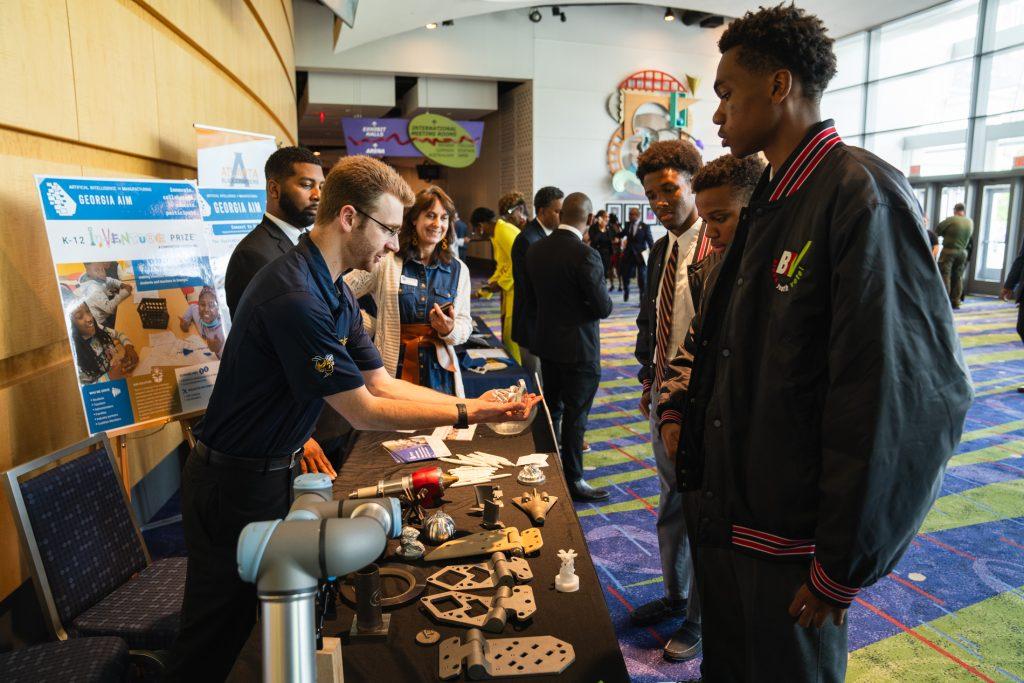 Kyle Saleeby, a research engineer with the Georgia Tech Manufacturing Institute, shows visitors how robotics can be used in manufacturing and an array of 3-D printed industrial materials.