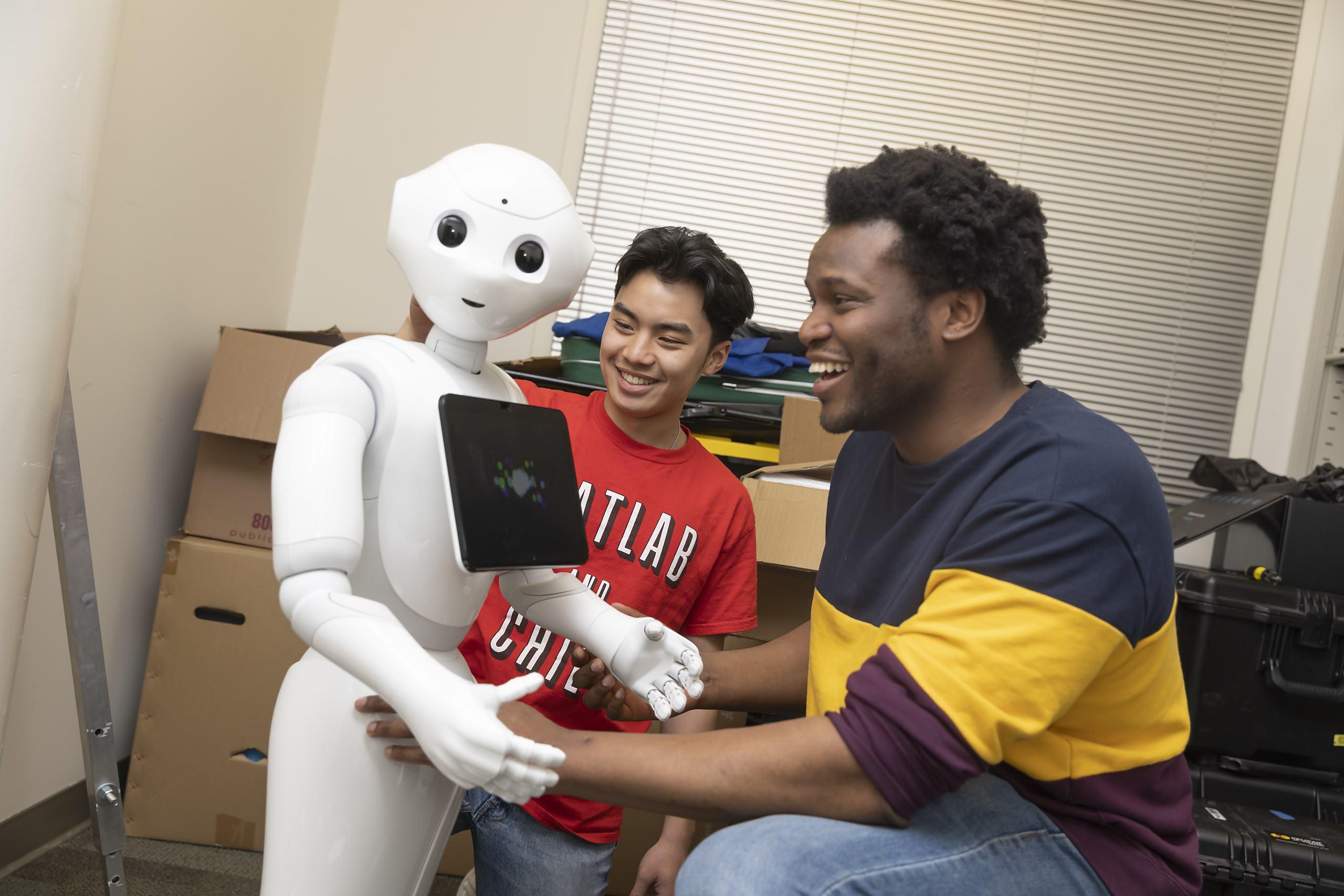 Two students interact with humanoid robot. 