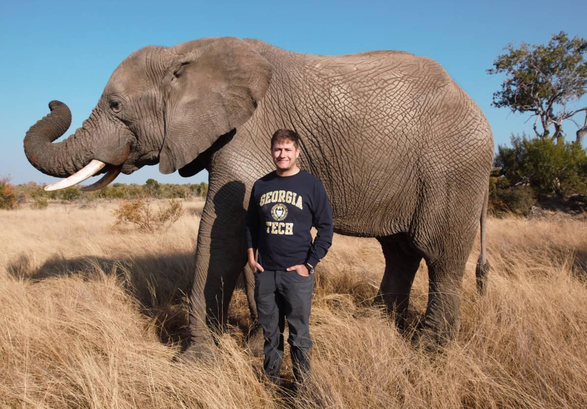 Georgia Tech mechanical engineering Ph.D. student, Andrew Schulz, standing in front of an elephant.