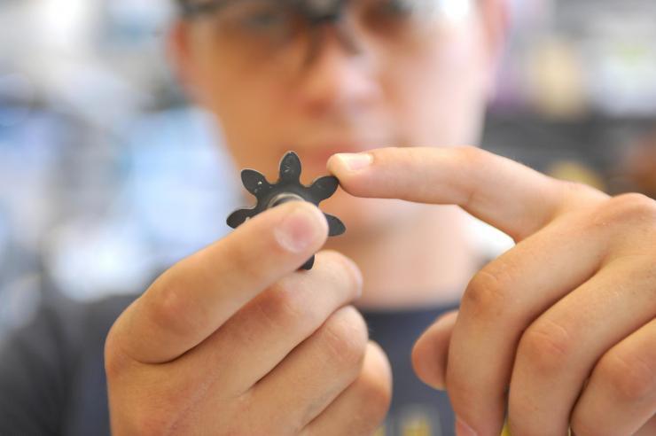 <p>Georgia Tech Graduate Student Caleb Amy holds a ceramic gear developed for a pump able to transfer molten tin at more than 1,400 degrees Celsius. (Credit: Christopher Moore, Georgia Tech)</p>