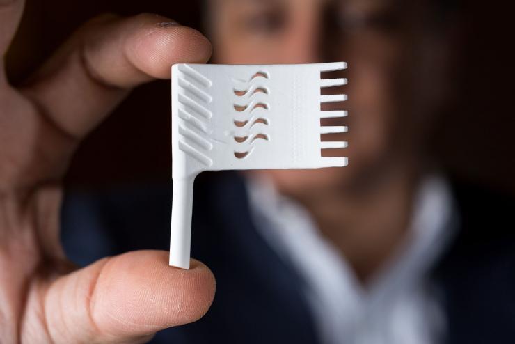 <p>Suman Das, Morris M. Bryan, Jr. Chair in Mechanical Engineering for Advanced Manufacturing Systems and Professor, holds a piece made by the LAMP System CPT6060, a 3D printer used for fabricating ceramic cores and molds used in making aircraft parts.</p>