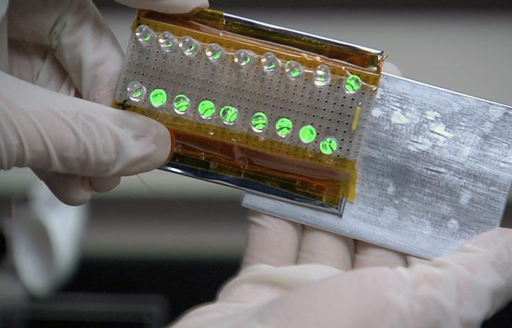 <p>Georgia Tech Professor Zhong Lin Wang led a team of researchers to develop generators based on the triboelectric effect. The device shown here uses the sliding motion of two different materials to produce enough electricity to light this row of bulbs. (Credit: Georgia Tech) </p>